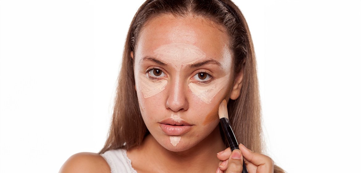Junge Frau nutzt dunklen Concealer als Contouring-Alternative an den Wangenknochen.